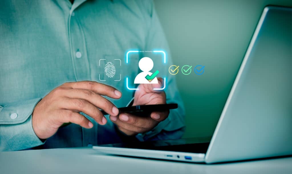 Employee using a smartphone for multi-factor authentication while working on a laptop